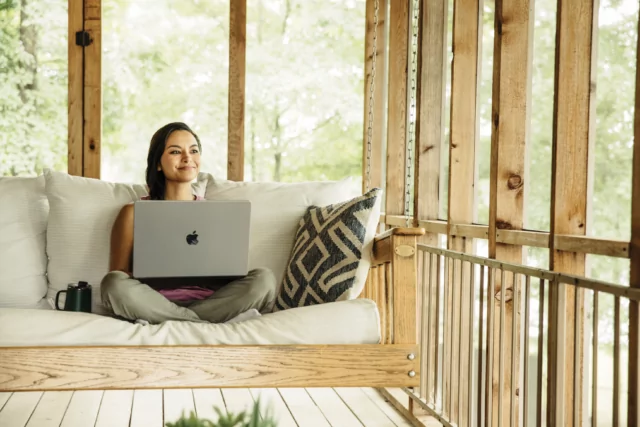 Woman using laptop at lake cabin